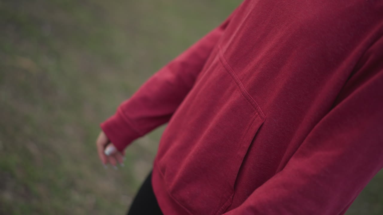 Casual Outdoor Activity In Park Setting, Person Finetuning Smartwatch While Warming Up Outdoors, Relaxed Individual In Hoodie Adjusting Wrist Device Before Engaging In Physical Activity