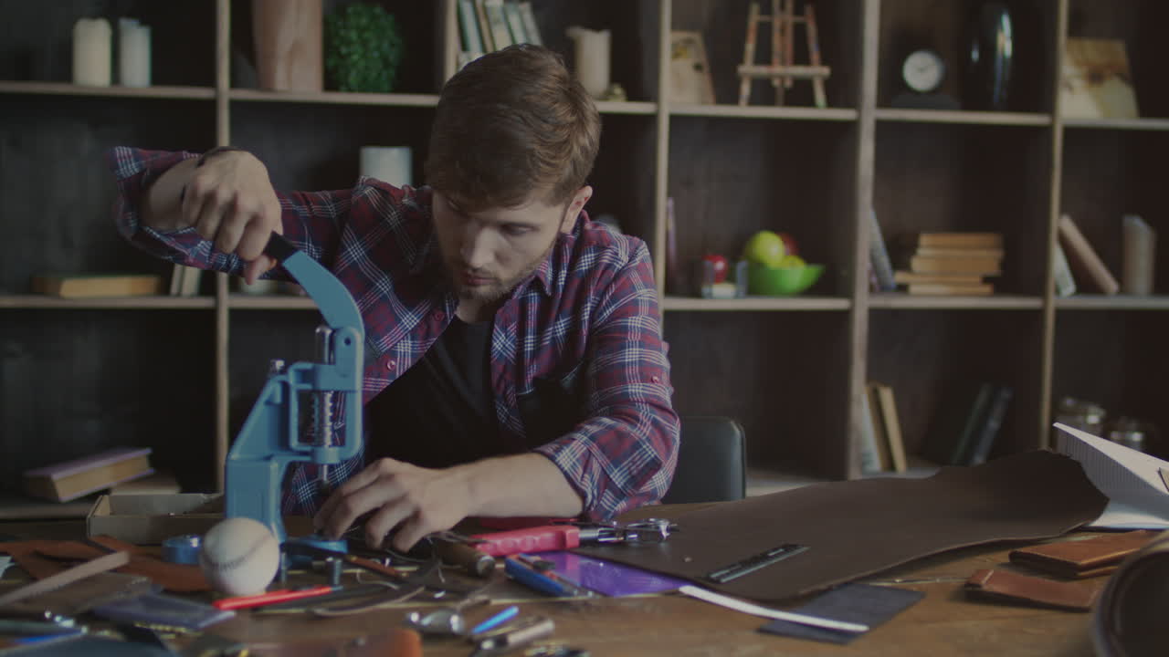 процесс изготовления кожаных изделий. мастер устанавливает заклепку на изделие