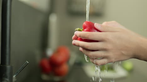 women's hands wash a bell pepper under tap water. slow motion video