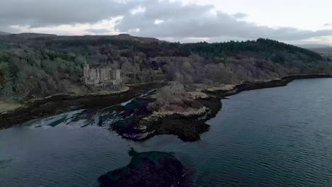 dunvegan castle on the isle of skye, surrounded by woodland and coastline at dusk, aerial view