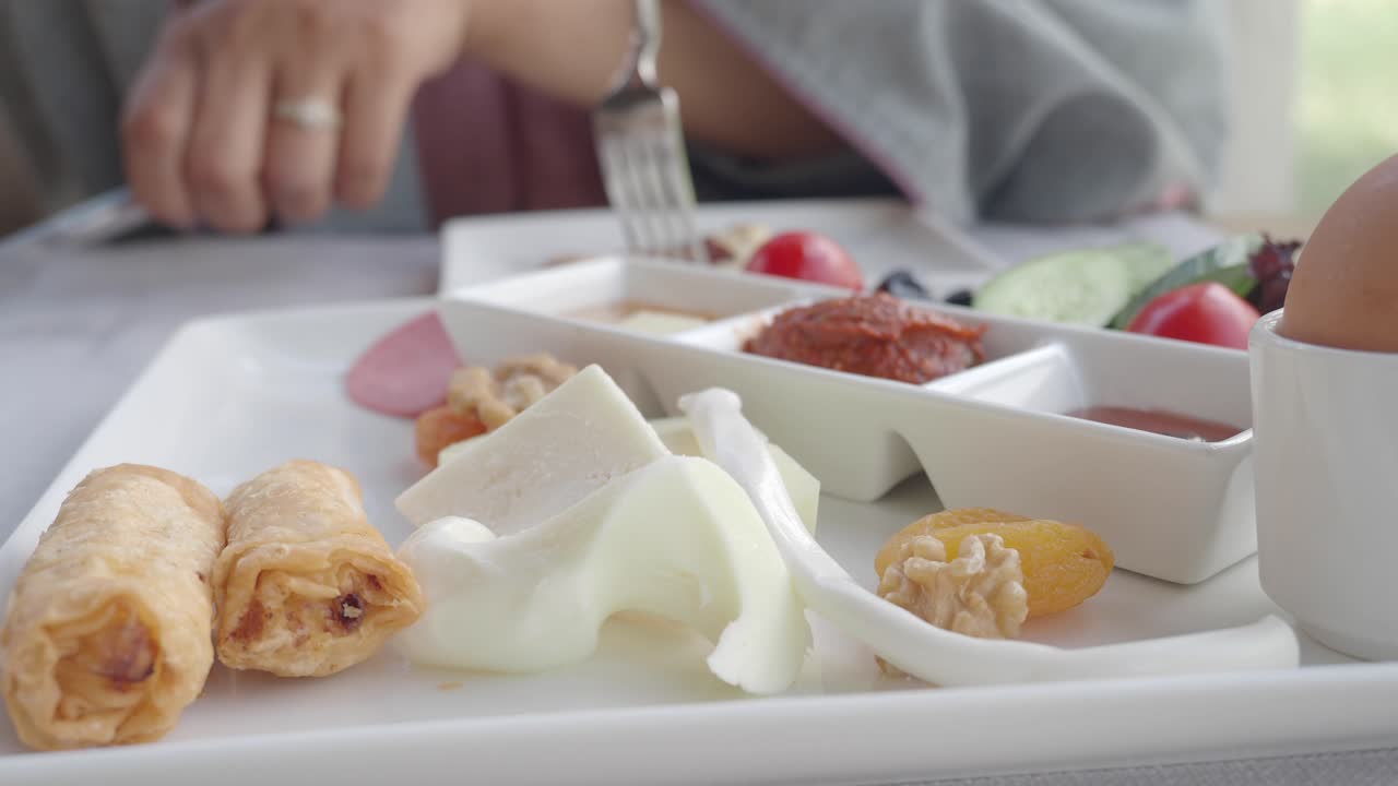 Breakfast plate with cheese, rolls, egg, tomato, cucumber, jam and olives