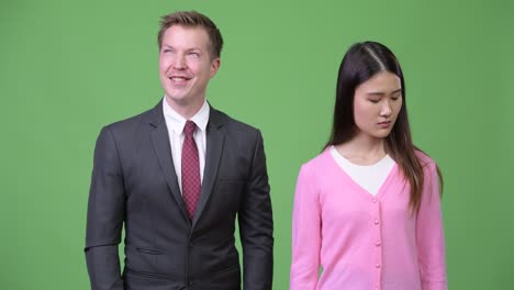 young sad asian woman and young happy businessman thinking together