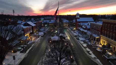 american flag waving in town square during colorful sunset on snowy winter evening