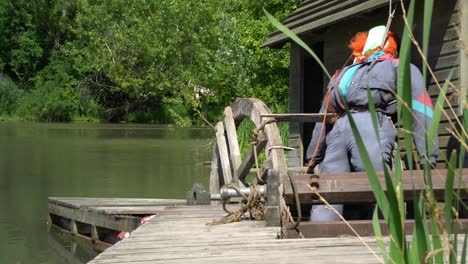 Creepy-practice-drowning-man-figure-next-to-decayed-old-small-watermill