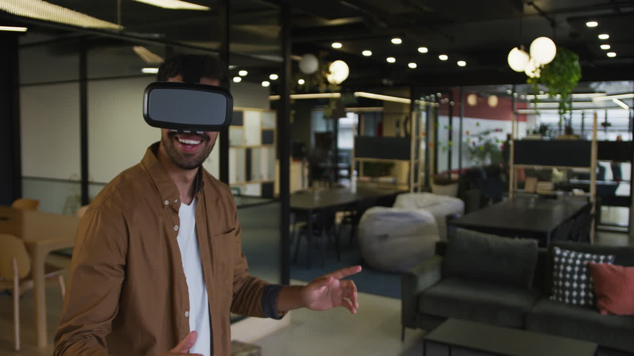 Uomo d'affari birazziale in piedi che utilizza un visore VR in un ufficio moderno