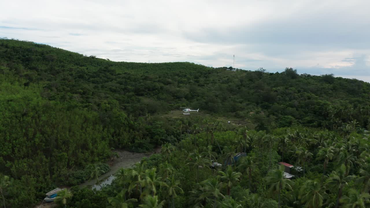 aterrizaje de helicóptero en el helipuerto en una isla remota verde durante un día nublado, aéreo