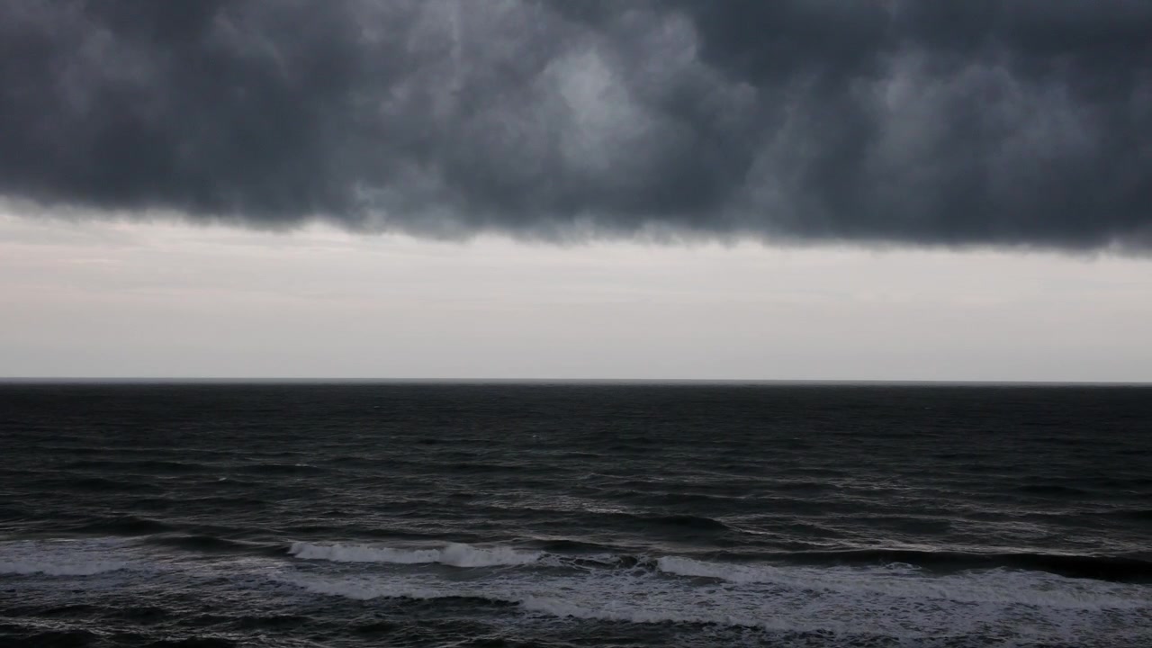 Nuvole temporalesche scure si avvicinano sull'oceano, creando un drammatico paesaggio marino costiero con un cielo minaccioso e tempo in cambiamento.