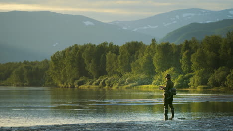 Fisherman-fishing-in-mountain-river-fjord,-amazing-landscape-at-sunrise,-wide-angle-view