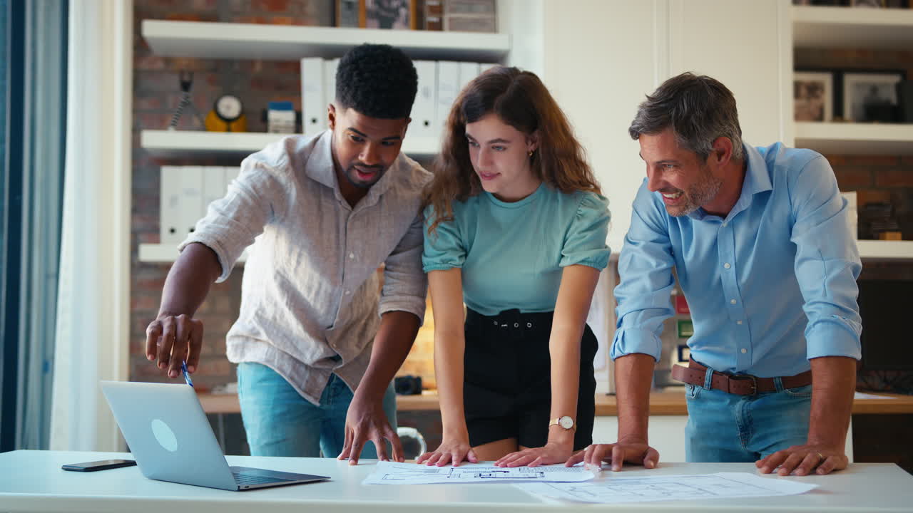 arquitectos masculinos y femeninos con computadoras portátiles se reúnen y discuten planes de construcción en una oficina moderna