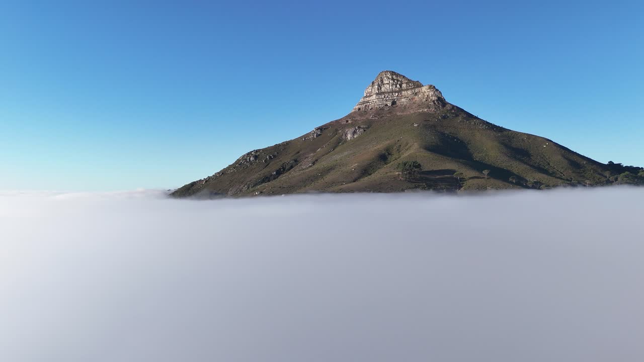 Aerial drone footage of Lion’s Head mountain in Cape Town, South Africa, surrounded by mist and clouds with only the peak emerging