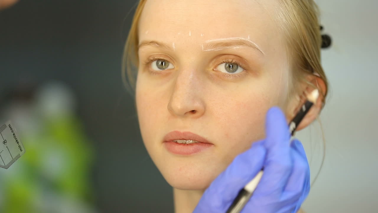 Cosmetologist applying special permanent makeup on woman eyebrows