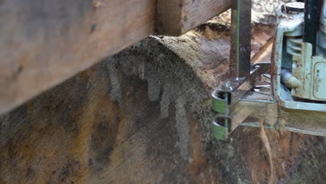 slow motion close-up shot of a chainsaw coming out of the end of a pine log at a homestead logging mill