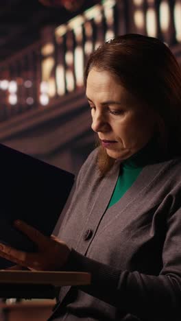 vertical video mature woman reading and writing at a university campus library
