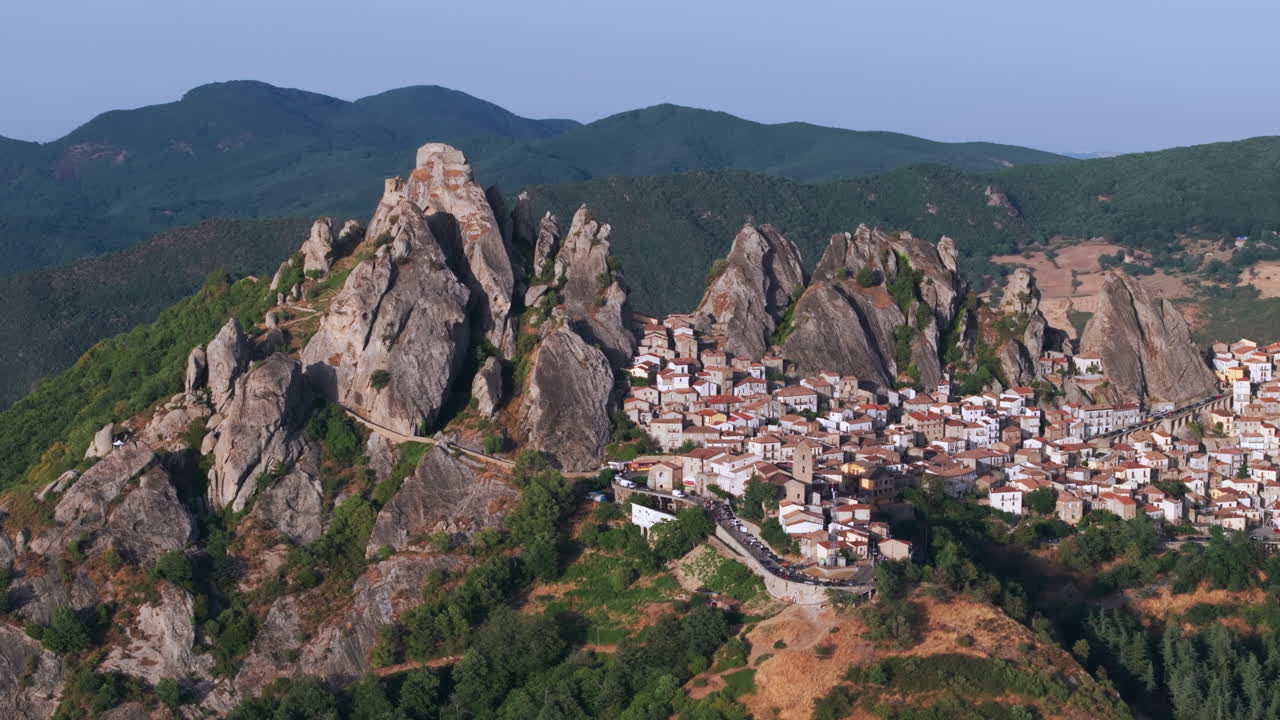 Aerial drone of Pietrapertosa, Italy—mountain village built into rocky peaks, terracotta roofs, sweeping valley views. Ideal for travel, tourism, culture, and cinematic landscape stock footage