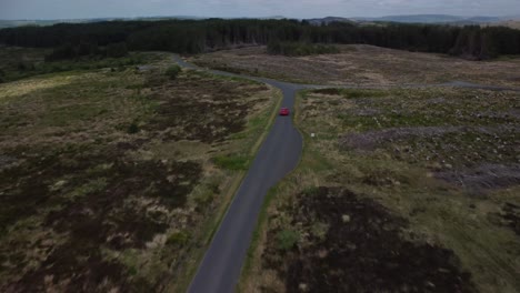 Camión-Rojo-Rastreado-Por-Un-Dron-Que-Viaja-Por-Una-Carretera-Rural-De-Una-Sola-Pista