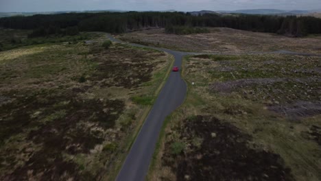 red car being tracked by drone travelling on a single track country road