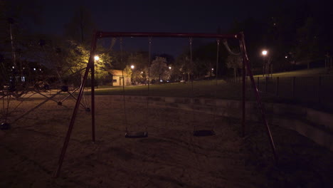 empty moving swings,playground at night,prague,czechia,during lockdown