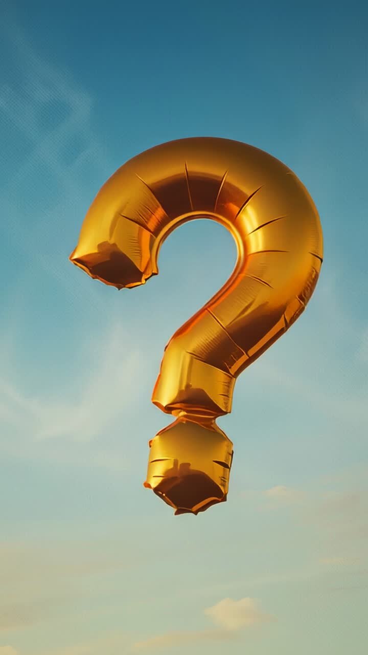Vertical video: Bobbing gold foil question-mark balloon rotating in blue sky, nudged by wind