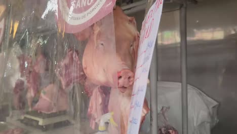 4k video of a pig's head behind a plastic film in meat market