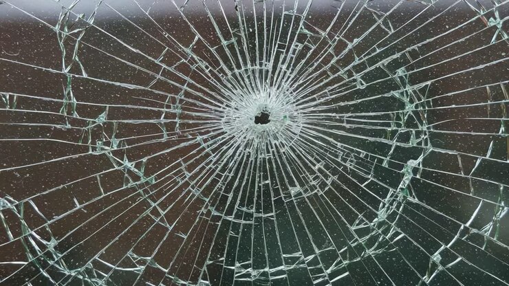 Stunning Close-Up of a Shattered Glass Surface Highlighting the Intricate Patterns and Radiating Cracks Formed Around a Central Impact Point