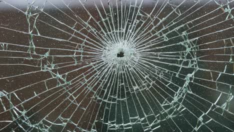 stunning close-up of a shattered glass surface highlighting the intricate patterns and radiating cracks formed around a central impact point