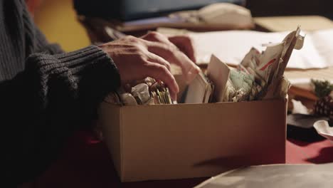 Person’s-hands-rifling-through-a-cardboard-box-of-old-letters-and-trinkets