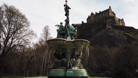 fountain in princes street gardens with water flowing and edinburgh famous castle in the background