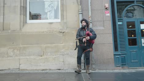 a street performer in a typical uk city plays a set of bag pipes