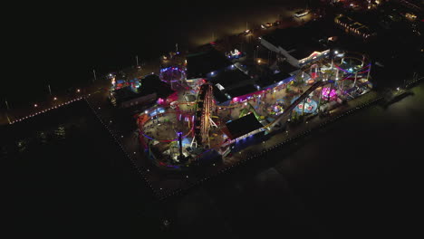 AERIAL:-Breathtaking-Birds-View-on-Santa-Monica-Pier-at-night-with-Ferris-Wheel-and-colorful-lights,