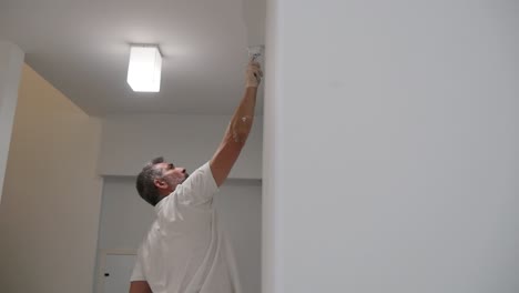 Professional-Painter-Reveal-From-White-Wall-Painting-Ceiling-Corner-With-Paint-Brush-In-Slow-Motion