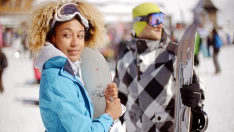 una mujer linda sosteniendo una tabla de snowboard en la pendiente de esquí