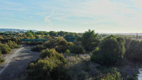 aerial forward to remote green railway bridge over a river in the spanish desert