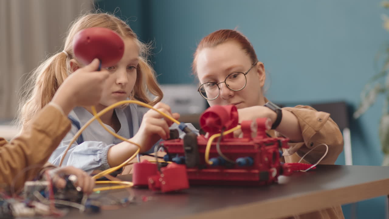 Female Teacher Helping Schoolgirl Constructing Robot during Lesson