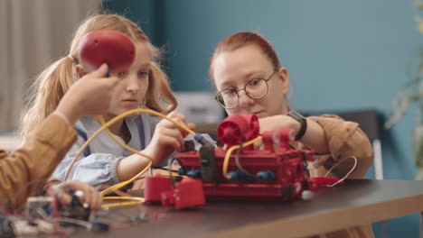 female teacher helping schoolgirl constructing robot during lesson