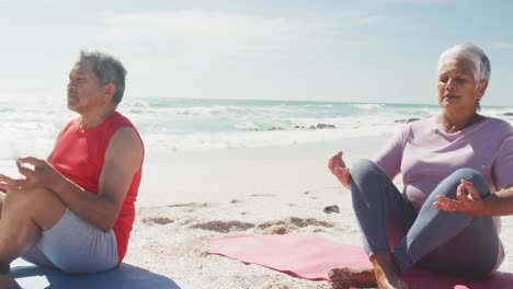 Relaxed-hispanic-senior-couple-practicing-yoga-on-mats-on-beach