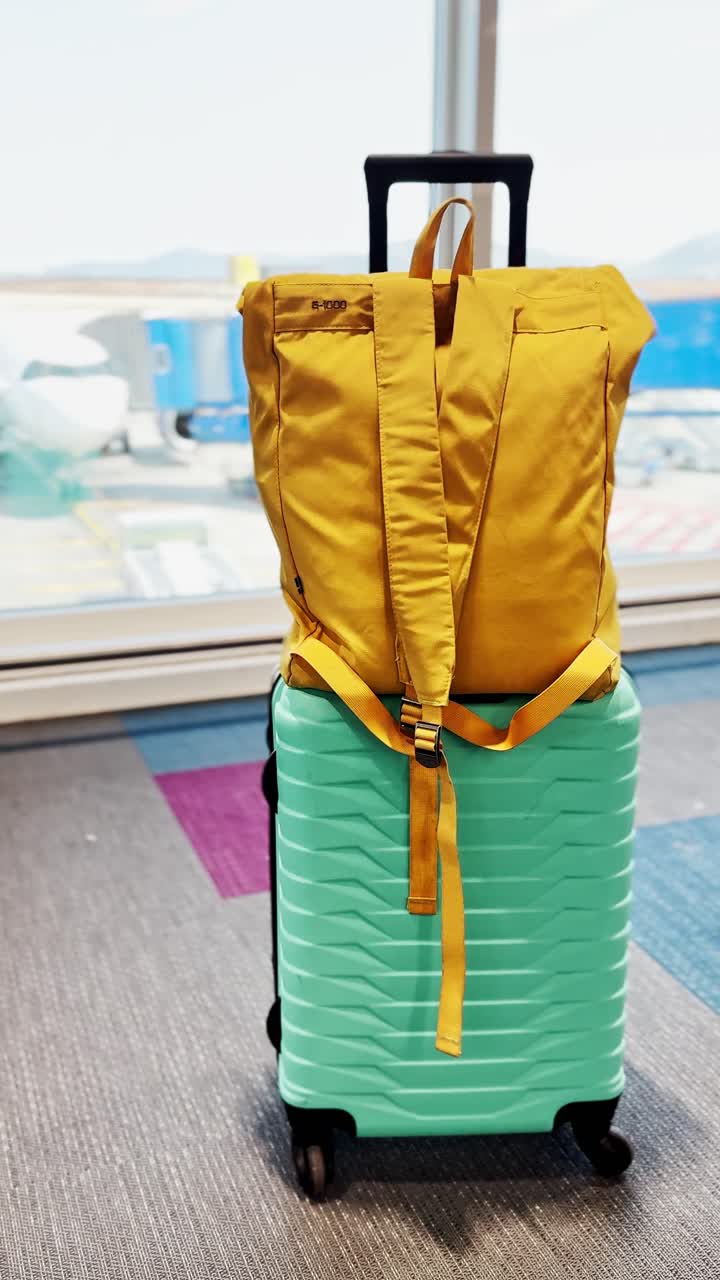 Close-up of Teal Suitcase and Yellow Backpack in Airport Lounge