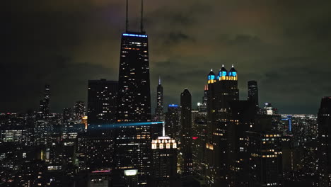 tomada estática de un dron de la noche iluminada por el horizonte de streeterville de la nublada chicago, estados unidos