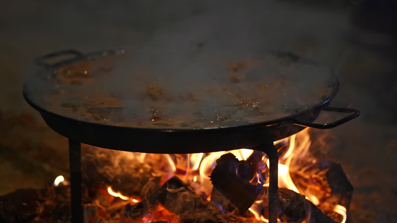 길에서 고전적인 빠에야 발렌시아나를 요리하는 동안 "paellero"라고 불리는 전형적인 팬으로 불에 가까이 하세요.