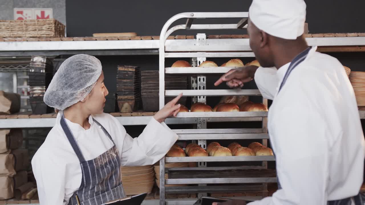 Padeiros diversos trabalhando na cozinha da padaria, contando pãezinhos com tablet em câmera lenta