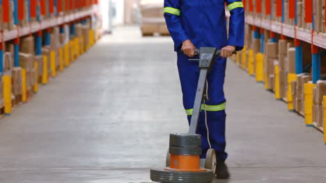 male warehouse worker cleaning warehouse floor