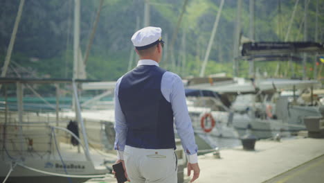 man in captain's hat walking along a harbor dock