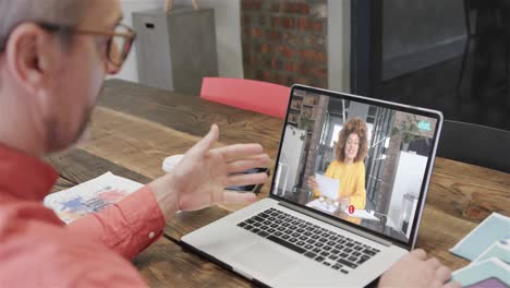 hombre de negocios caucásico en una llamada de video portátil con una colega afroamericana en la pantalla