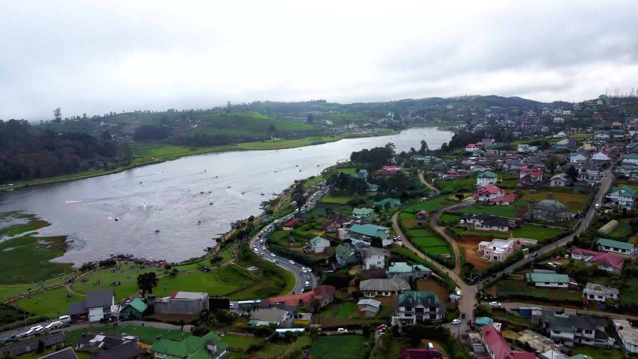 volando sobre casas coloniales en nuwara eliya hacia el maravilloso lago gregory donde la gente disfruta de actividades acuáticas, sri lanka