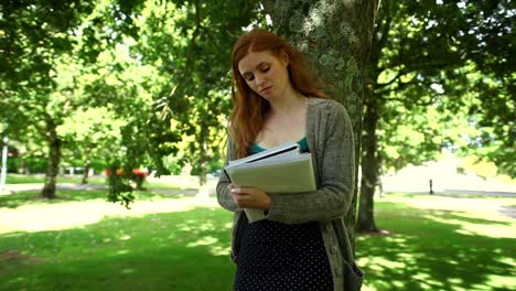 una hermosa pelirroja pensando haciendo tareas de pie en el parque