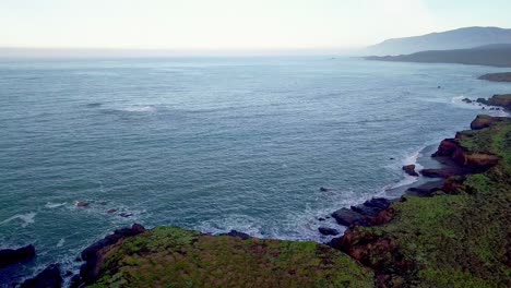 Aerial-view-of-waves-crashing-on-beach-and-cliffs-on-California-coast