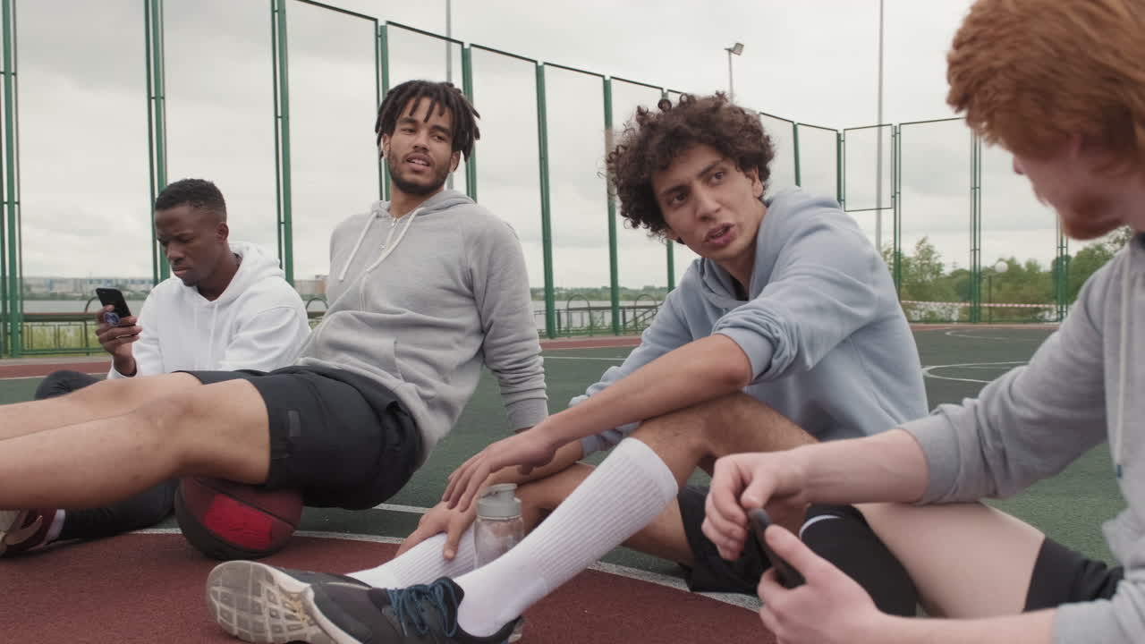 Amici che si riposano su un campo da basket all'aperto