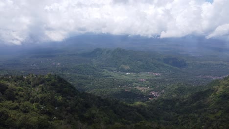 Aerial,-flying-past-a-man-standing-on-Lahagan-sweet-view-Platform-overlooking-lush-green-valley-villages,-Bali