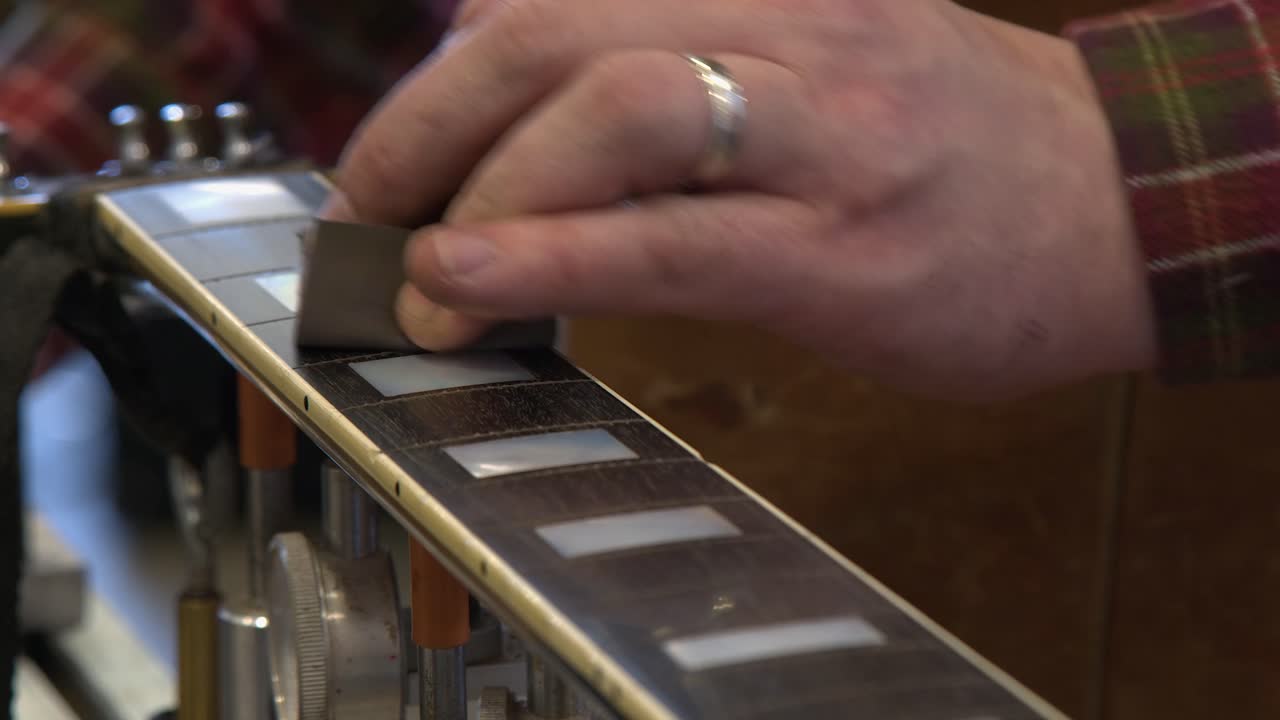 Carta vetrata a grana fine fa brillare la tastiera di chitarra in ebano, primo piano