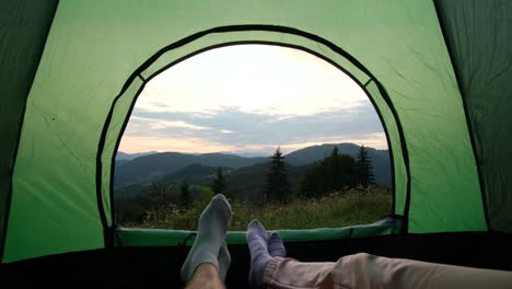 Tourists with Tents Rest in the Mountains on a Meadow a View of a Tourist Campsite with Tents and an Electric Car where Tourists are Resting on a Glade among Trees and Fog Creeping over the Forest a Tent City on a Hike on an Early Sunny Foggy Morning