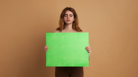 young woman worried and upset holding a green panel